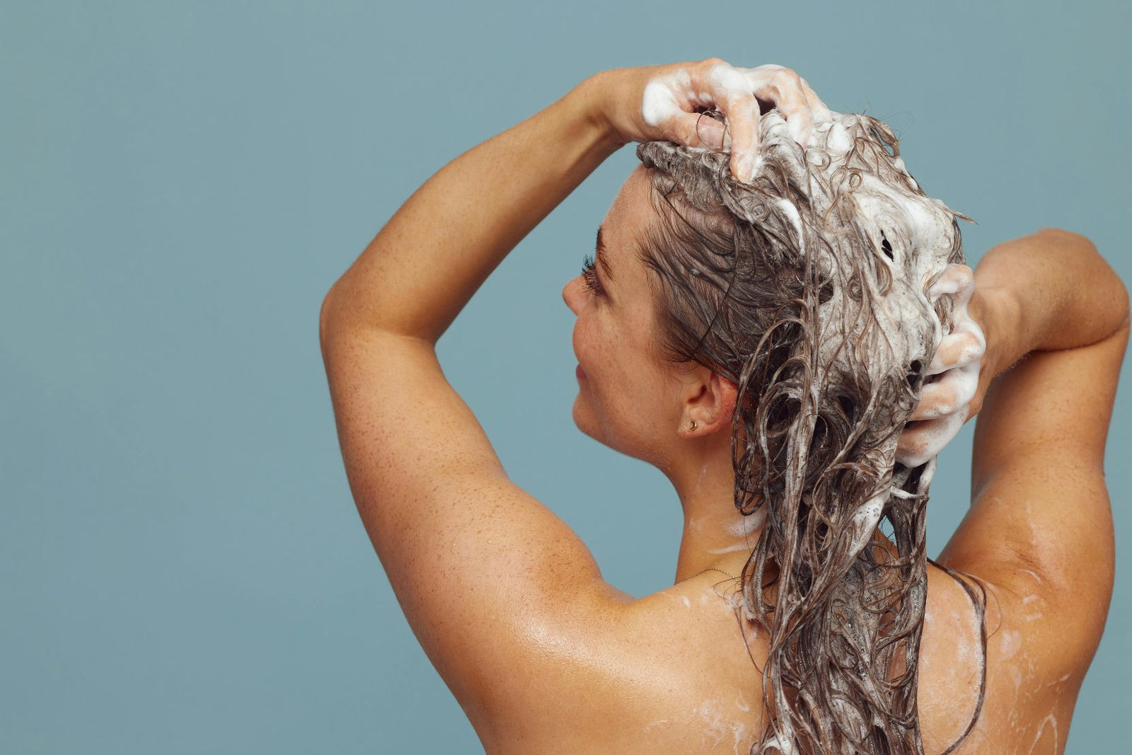 Woman in shower shampooing her hair.